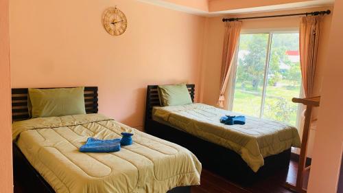 two beds in a room with a clock on the wall at Yada Resort Koh Yao Noi in Ko Yao Noi