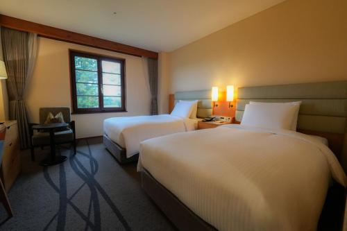 a hotel room with two beds and a window at Lotte Arai Resort in Myoko