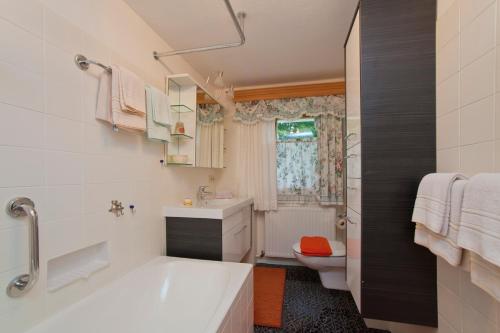 uma casa de banho com uma banheira, um lavatório e um WC. em Haus Waldrand em Oberndorf in Tirol