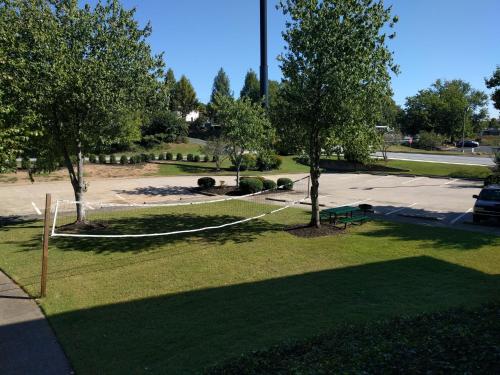 a net in a park with trees and a parking lot at Brick Lodge Atlanta/Norcross in Norcross