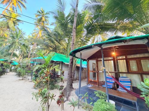 een klein huis aan het strand met palmbomen bij Lacto Cressida in Palolem