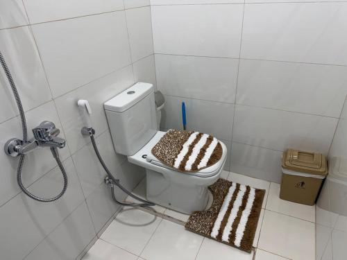 een badkamer met een toilet en een bruin-wit tapijt bij Sky5 Apartment in Hatta
