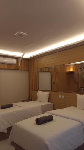 een hotelkamer met drie bedden en een scherm bij 7 Day Inn in Gili Trawangan