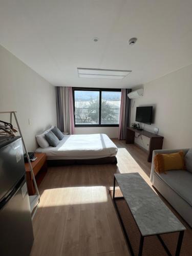 een woonkamer met een bed en een bank bij Living in Jeju Island in Jeju-stad