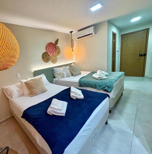 two beds in a hotel room with towels on them at Studio Praia de Carneiros in Praia dos Carneiros