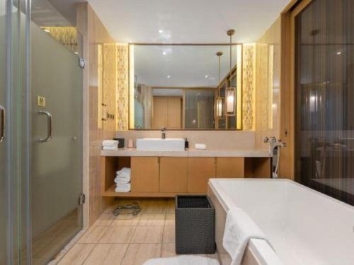 een badkamer met een bad, een wastafel en een spiegel bij Wojo Hotel in Tashan