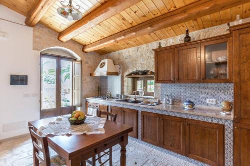 cocina con armarios de madera y mesa de madera en La Dimora del Decano, en Scicli