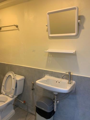 a bathroom with a toilet and a sink and a mirror at Uncle Yo House in Ban Tha Khreng