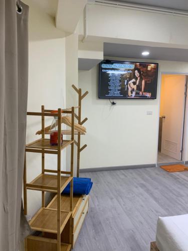 a room with a tv on the wall and a shelf at Uncle Yo House in Phuket