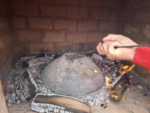 une personne cuisine au-dessus d'un feu dans un four en briques dans l'établissement Green cottage, à Blidinje
