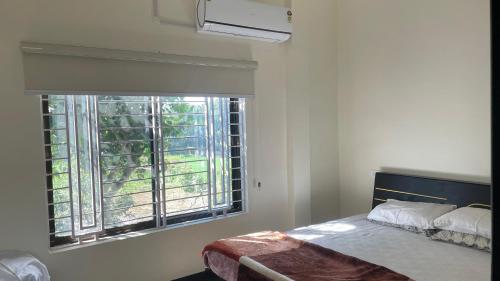 een slaapkamer met een bed en een groot raam bij Neevah Farm in Sehore