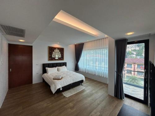a bedroom with a bed and a large window at Phranang Place- SHA Extra in Ao Nang Beach