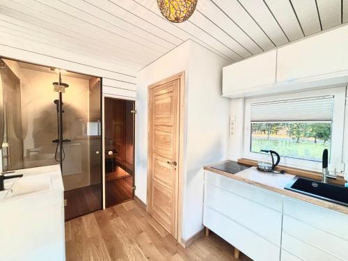 a kitchen with white cabinets and a sink and a window at Namelis su sauna SMILGA in Radailiai