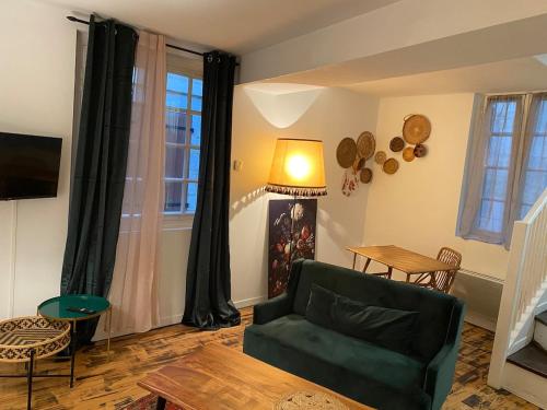 ein Wohnzimmer mit einer grünen Couch und einem Tisch in der Unterkunft La source, maison de ville vieux Périgueux in Périgueux