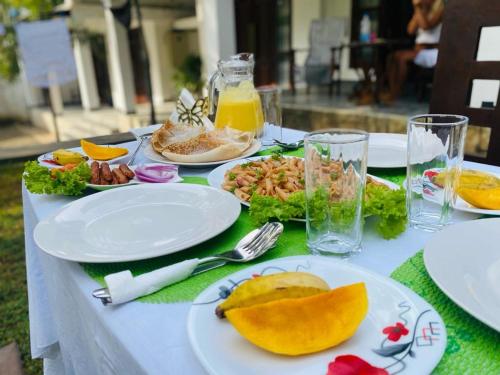 een witte tafel met borden voedsel erop bij Ibeeza Motel - Bathigama in Dikwella