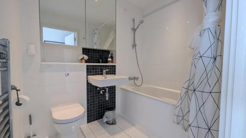 a bathroom with a sink and a toilet and a tub at Stylish 2BR Serviced Apartment by Ellbee Apartments in Hemel Hempstead
