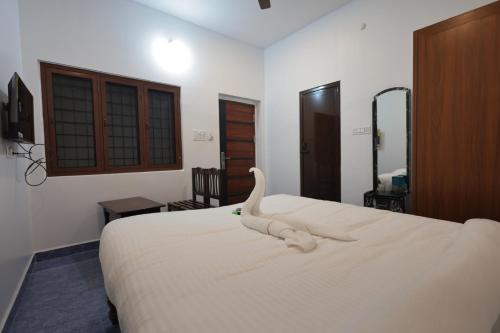 ein Schlafzimmer mit einem weißen Bett mit einem Schwan darauf in der Unterkunft AK Residency Auroville in Kuilapayam