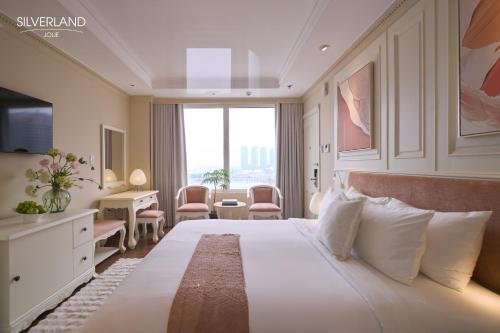 een hotelkamer met een bed, een bureau en een raam bij Silverland Jolie Hotel in Ho Chi Minh-stad