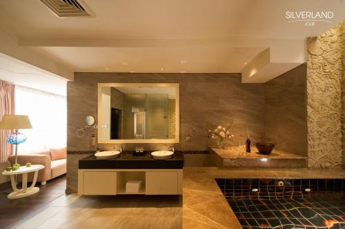 een badkamer met een wastafel en een grote spiegel bij Silverland Jolie Hotel in Ho Chi Minh-stad