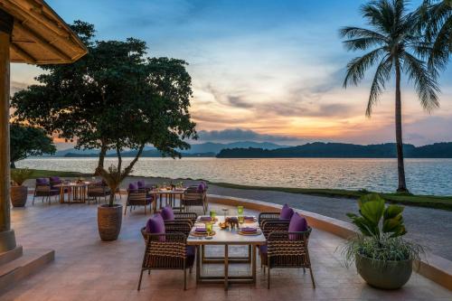 a restaurant with a view of the water at sunset at The Naka Island, a Luxury Collection Resort & Spa, Phuket in Ko Naka