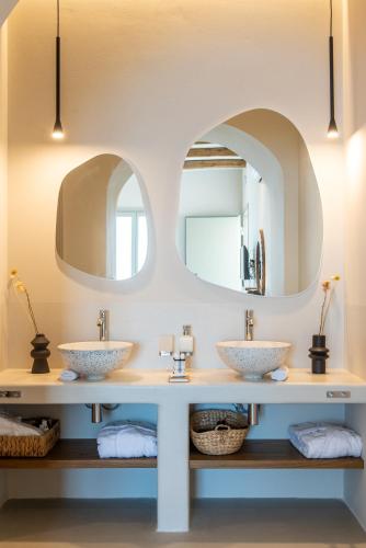 two sinks in a bathroom with two mirrors at Althea Anafi Suites in Anafi
