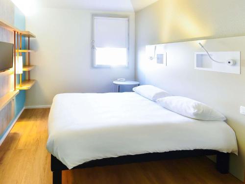 une chambre avec un grand lit blanc avec une fenêtre dans l'établissement Ibis budget Dijon Centre Clemenceau, à Dijon