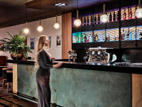 een vrouw die achter een bar in een restaurant staat bij Arche Hotel Puławska Residence Warszawa in Warschau