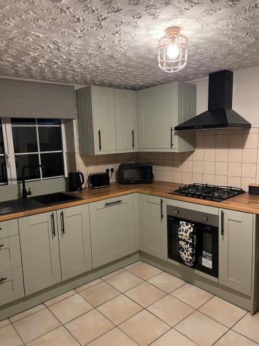 a kitchen with white cabinets and a stove top oven at Cute and cosy cottage in the lovely Oxton village in Birkenhead
