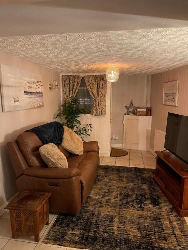 a living room with a brown couch and a television at Cute and cosy cottage in the lovely Oxton village in Birkenhead