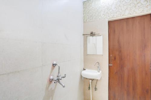 ein Badezimmer mit Waschbecken und Holztür in der Unterkunft Hotel O Heritage Inn in Prayagraj