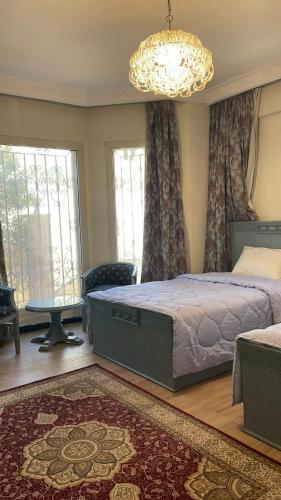a bedroom with a large bed and a chandelier at فيلا كامله للايجار in Kafr Ghaţāţī