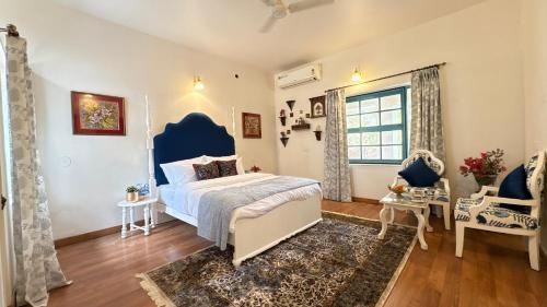 een slaapkamer met een blauw bed en een raam bij Seclude Hampi 1800 in Jāmb