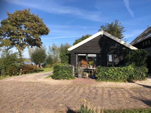 a black house with a driveway in front of it at Gastenhuisje De Donk in Brandwijk