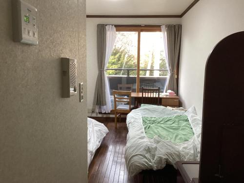 una camera con un letto, un tavolo e una finestra di 森のハイジ ad Azumino