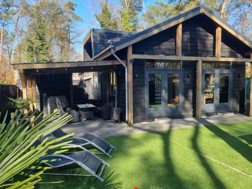 a log cabin with a patio and lawn at Vakantiehuis Veluws Genieten met whirlpool en sauna in Doornspijk
