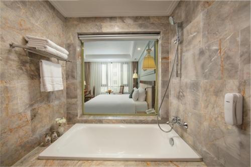 ein Badezimmer mit Badewanne und großem Spiegel in der Unterkunft Hanoi Pearl Hotel in Hanoi