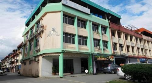 a building on a street with cars parked in front of it at Hotel Perdana in Lawas
