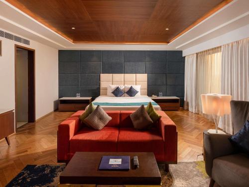 a bedroom with a bed and a red couch at Novotel Vijayawada Varun in Vijayawāda