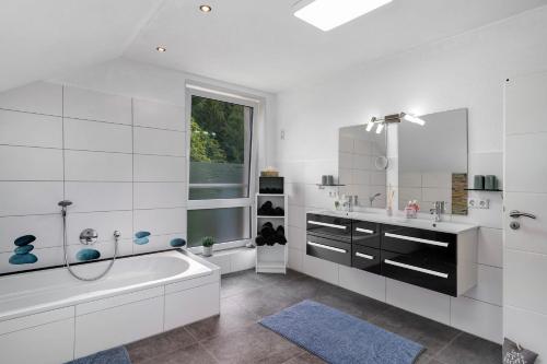 een witte badkamer met een bad en een wastafel bij Villa Eichwald Appartements in Freudenstadt