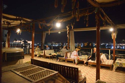 een groep mensen die 's nachts op een balkon zitten bij Nefertiti Hotel Luxor in Luxor
