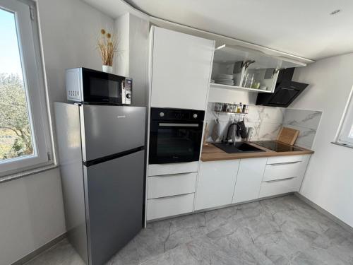 een keuken met witte kasten en een roestvrijstalen koelkast bij Green view apartment in Koper