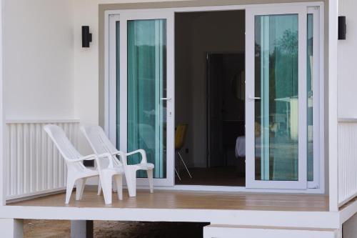 two white chairs sitting on the porch of a house at Travellers Palm in Koh Phangan