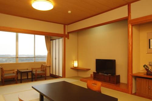 sala de estar con mesa y TV en Kashikojima Park Hotel Michishio en Shima