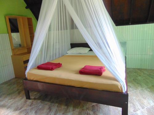 een bed met twee rode kussens in een kamer bij Brother Bungalow in Gili Trawangan