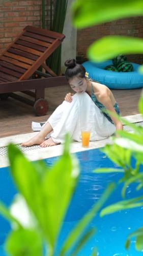 a woman sitting on the floor next to the water at La ALBA Beach Villa in Hoi An