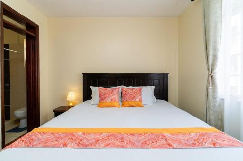 a bedroom with a bed with two orange pillows at Royal Homes in Nairobi