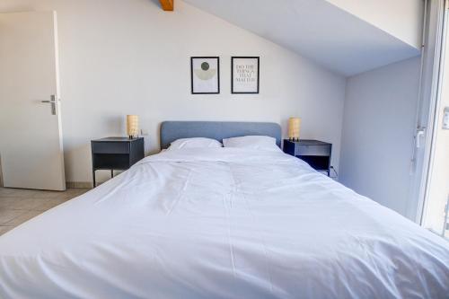 un grand lit blanc dans une chambre avec deux tables de nuit dans l'établissement La tribu, à Périgueux