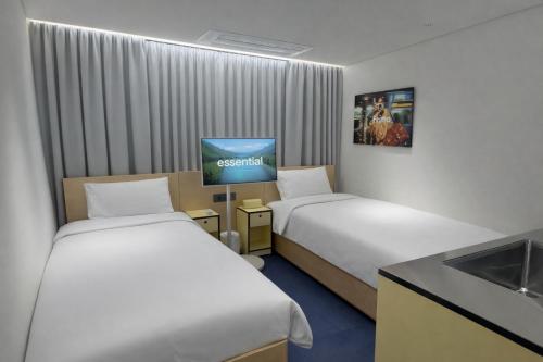 a hotel room with two beds and a flat screen tv at Fritta Hotel in Suwŏn-yŏk