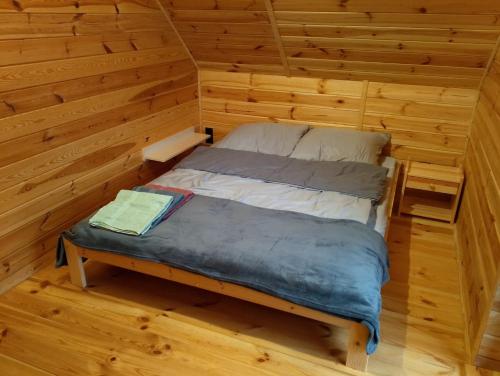a small bed in a room with wooden walls at Miodowa cisza in Szafarnia