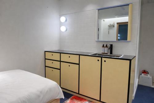 a bathroom with a sink and a bed with a mirror at Fritta Hotel in Suwŏn-yŏk